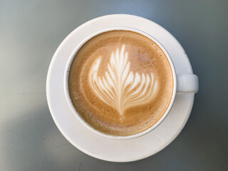 A cup of coffee latte on a grey table. A mug of flat white coffee on a grey background. Coffee art. Heart flower shape latte art. Copy space.