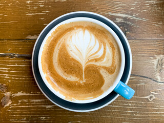 A cup of coffee latte on a wooden table. A mug of flat white coffee, latte, cappuccino on a wooden background. Coffee art. Heart flower shape latte art