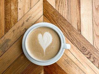 A cup of coffee latte on a wooden table. A mug of flat white coffee, latte, cappuccino on a wooden background. Coffee art. Heart flower shape latte art