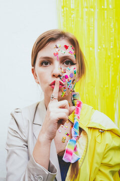 Woman with finger on lips in front of two tone wall