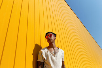 Young man wearing white t-shirt leaning at yellow wall
