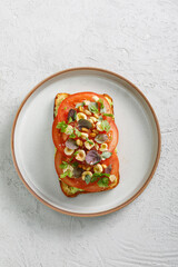 Toast with guacamole and slices of fresh tomatoes with fried hazelnuts on top. Vegetarian cuisine