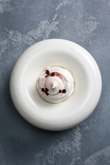 Obraz na płótnie Canvas Pavlova dessert in white bowl over black background. Meringue dessert.