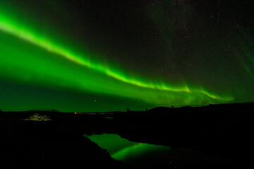 Aurora Borealis green beams with lake reflection