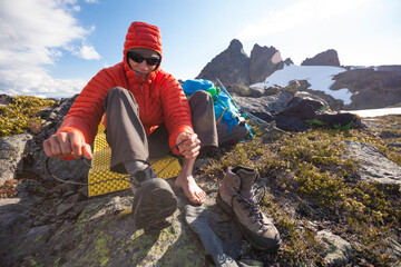 A climber laces up his boots in preparation to climb a neaby mountain.