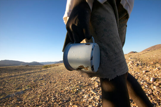 Himba boy with cup heading to waterhole northern Namibia.