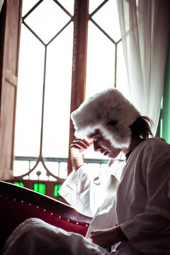 Androgynous woman in alpaca hat sits in window of Spanish colonial fla