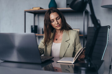 Woman works at office sitting at her desk with her laptop