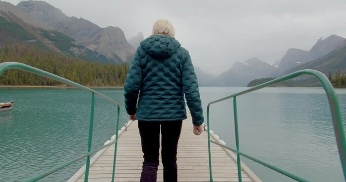 Outdoorsy woman walking down a pier on a stunning lake in the canadian Rocky Mountains.
Stunning green lake near Jasper surrounded by mountain peaks.
