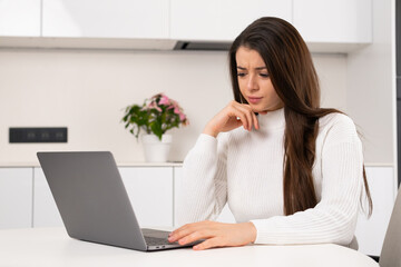 Disappointed female feeling hopeless at work sitting at the desk and using laptop. Failure life concept