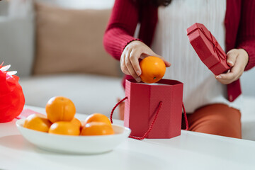 Asian Woman holding mandarin oranges with red gift box thankful present Lunar New Year. Chinese...