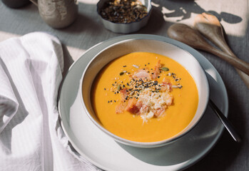 Delicious pumpkin cream soup with seeds and bacon. Vegetable seasonal soup.