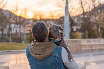 Hombre reconocible abrazando a su perrita, en el parque.