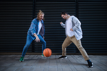 Man with down syndrome playing basketball outdoor with his friend. Concept of friendship and...