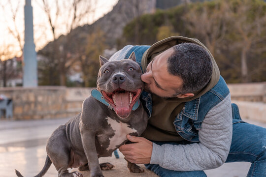 Hombre besando a su perrita en el parque.
