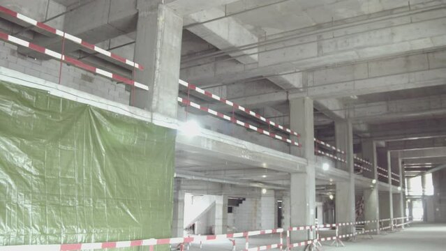 Long empty corridor with columns and color striped tapes in sports stadium building hall. Athletic arena construction site
