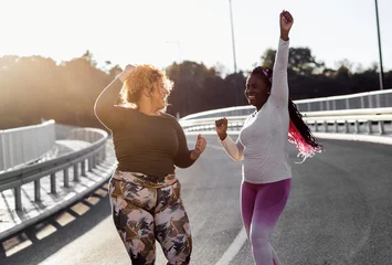 Deurstickers Two excited young plus size women jogging together. © Zoran Zeremski