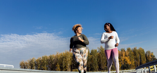 Two young plus size women jogging together.