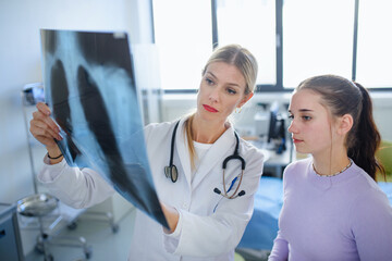 Young woman doctor showing x-ray image of lungs to her patient.