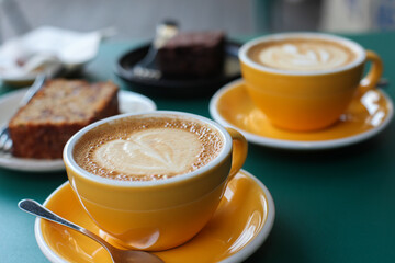 Two cups of flat white coffee, banana bread, brownie on a green tale 