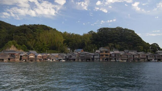 Wider dolly shot from boat of The Ine no Funaya (a large cluster of traditional houses) . Houses are private houses, located in the Ine area of Ine-cho Town, Yosa-gun County, Kyoto Prefecture.