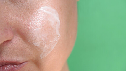 Part of a woman's face with cream on her cheek. The texture of the skin with enlarged pores.