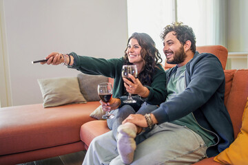 Loving couple drinking wine and watching tv sitting on the couch