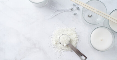 ingredients for candle making , soy wax flakes, candles, wicks on light marble background