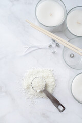 ingredients for candle making , soy wax flakes, candles, wicks on light marble background