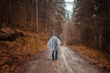 Fototapeta premium man in raincoat walks through forest, rain, loneliness, autumn and winter, man inside himself, reflections.