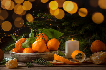 Fototapeta na wymiar Christmas tangerines and fir branches on a wooden table. Fir branches and a candle create a holiday mood