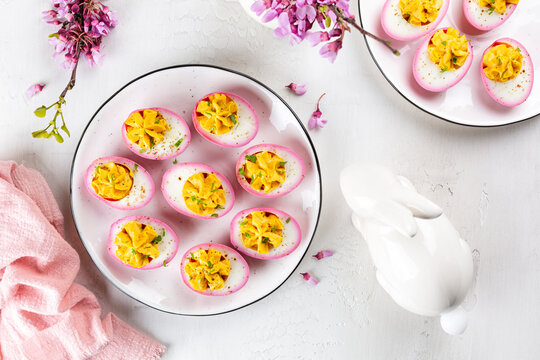 Stuffed Pink Deviled Eggs with  pepper and mayonnaise colored with beetroot. Easter food concept, spring flowers, easter bunny. Top view.