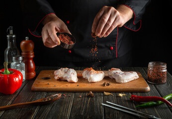 Professional chef adds aromatic spices to raw chicken wings. Cooking chicken nugget in the restaurant kitchen. Copy space