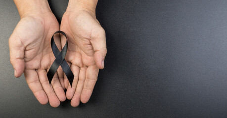 Hand hold black ribbon on background.
Bereavement and Mourning is the grieving process concept.
