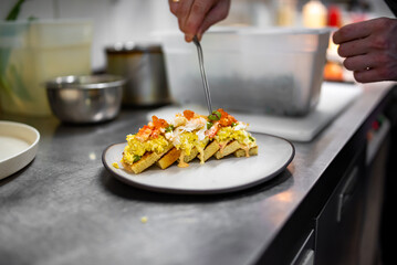 chef cooking brioche with scrambled eggs, caviar and crab meat on kitchen