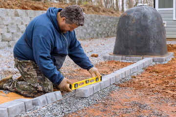 Master lays paving stones in garden pavers stone pathway paving by professional paver worker.