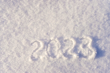 Text 2023 written on white fresh sparkling snow on sunny winter day. Merry Christmas and Happy New Year. Winter holiday concept. Flat lay, top view, copy space