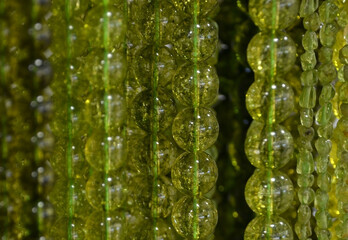 Green olivine stone or peridot gemstone beads as a background. Selective focus.
