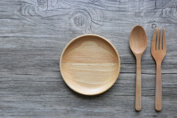 Wooden bowl with spoon and fork on wooden background