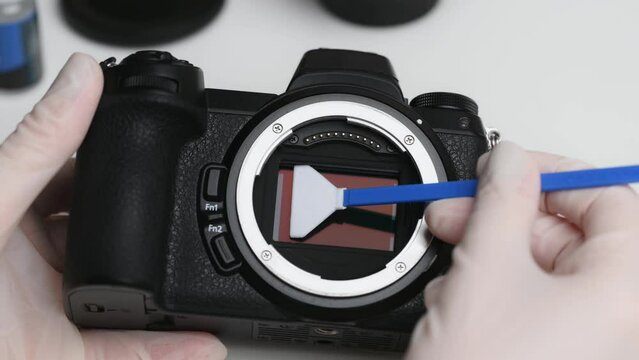 Cleaning the camera sensor with sensor cleaning swab from dust and dirt.Cleaning and maintenance of the mirrorless camera sensor. Care concept for professional photography equipment. Close-up.