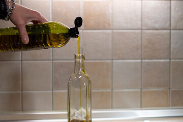 A stream of sparkling extra virgin olive oil, AOVE, as it pours from the plastic container into a...