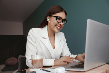 Young beautiful joyful woman smiling while working with laptop in office. Girl are using computer.