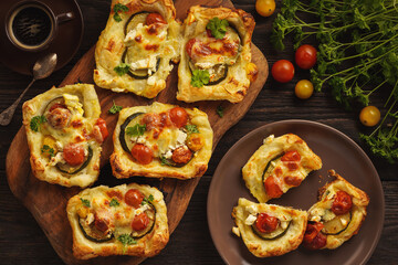 Crispy puff pastry mini tarts with zucchini, tomatoes and cheese. 