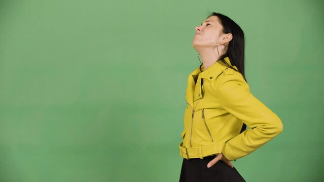 A young beautiful Caucasian woman has a backache - green screen studio