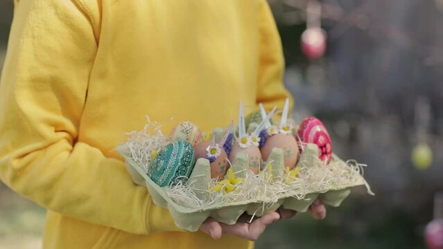 Girl keeps decorated Easter eggs in the palms