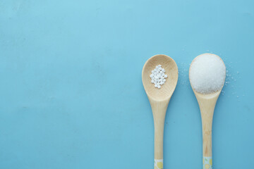 artificial sweetener container comparing with white sugar on wooden spoon 