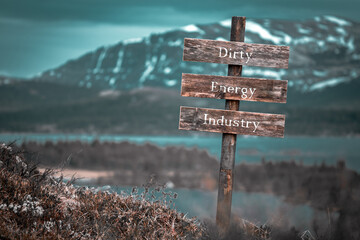 dirty energy industry text quote engraved on wooden signpost outdoors in landscape looking polluted and apocalyptic.