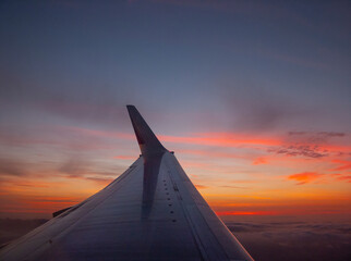 Tragfläche eines Flugzeuges bei Abenddämmerung über den Wolken

