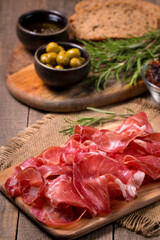 Italian slices of coppa, capocollo, capicollo, bresaola or cured ham with rosemary. Raw food.  