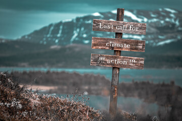 last call for climate action text quote engraved on wooden signpost outdoors in landscape looking...
